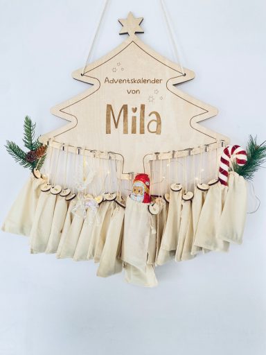Ein hölzernes Schild in Form eines Weihnachtsbaums mit dem Namen Mila und Geschenktüten.
