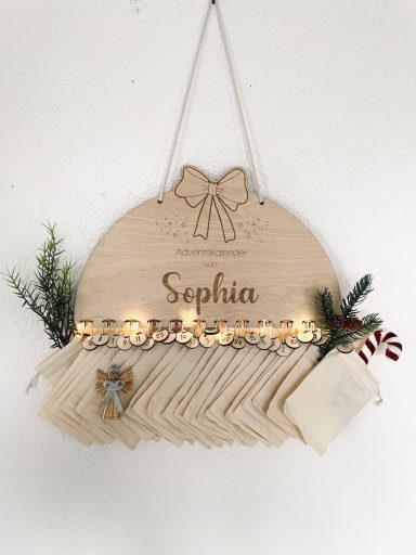 Holztäfelchen mit dem Namen „Sophia“, geschmückt mit Weihnachtsmotiven und Lichtern.